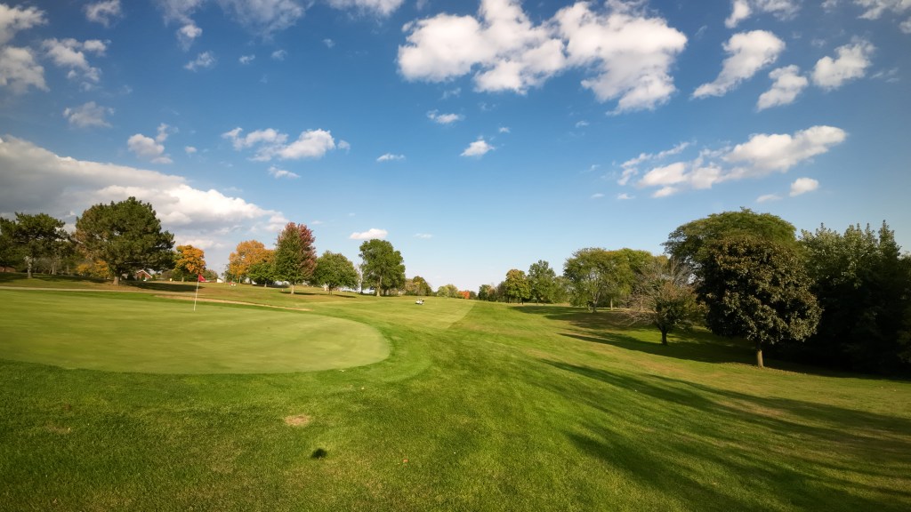 View from behind green and down fairway with blue skies