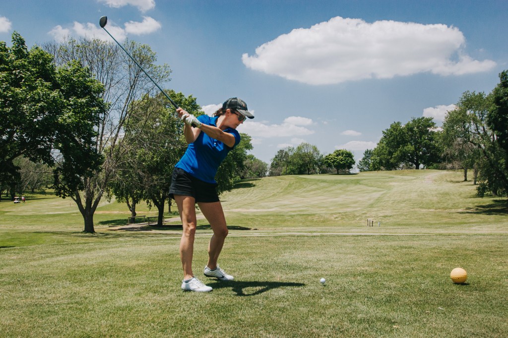 Female golfer hitting tee shot from tee box