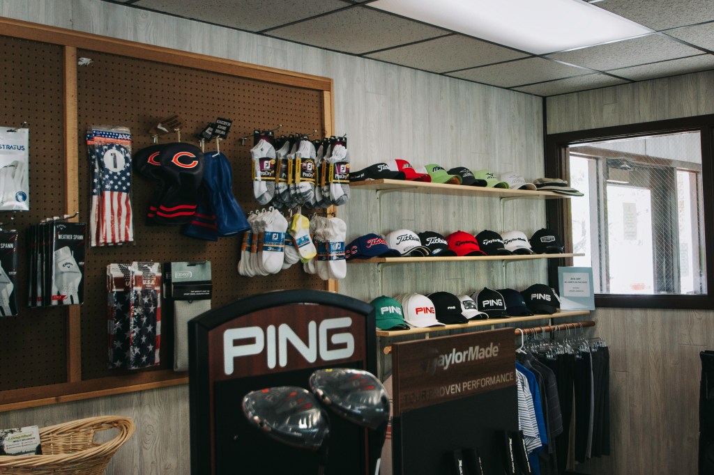 Inside shot of pro shop with golf clubs, accessories, and headwear