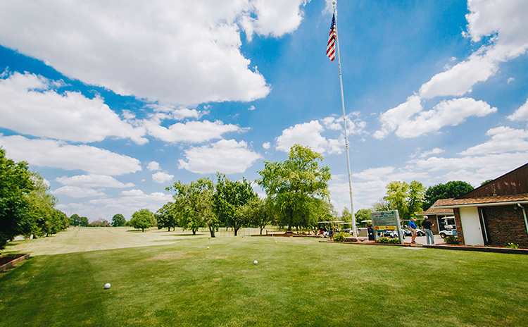 View of golf course green with American flag flying in the foreground