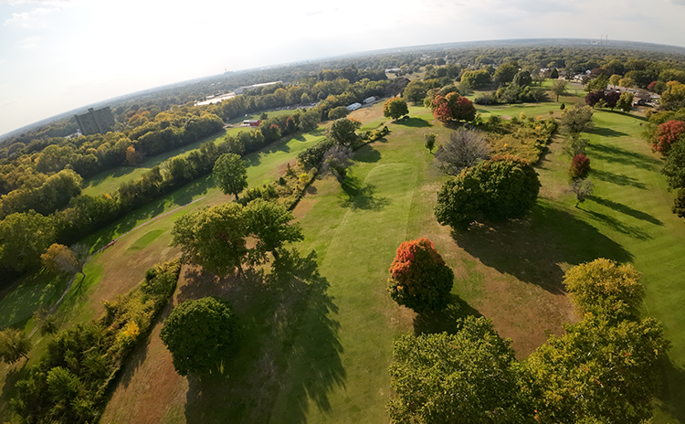 Bird's eye view of golf course fairway with autumnal trees